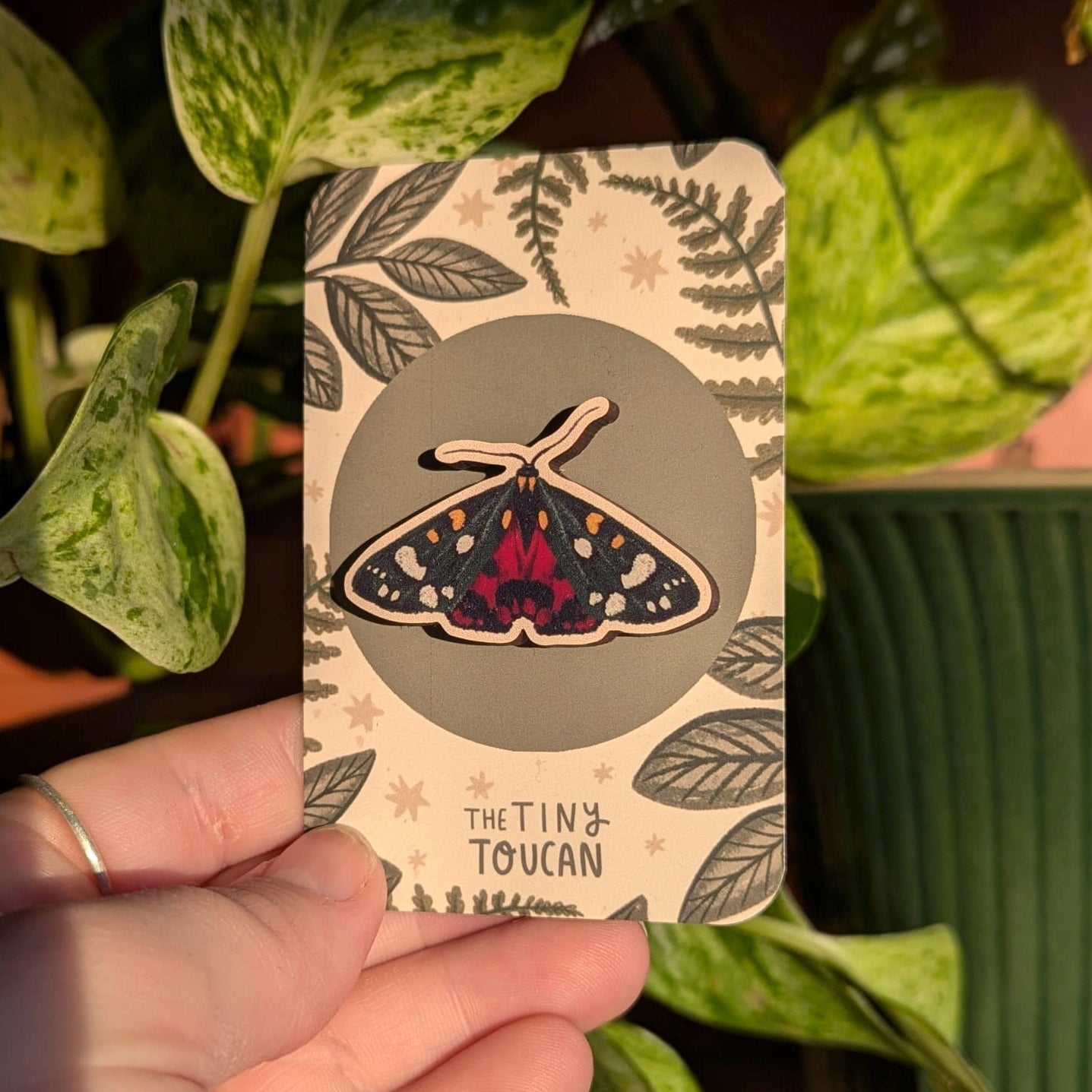 Card with a butterfly design held by a hand against a leafy background